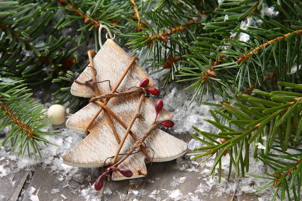 Weihnachtsbaumanhänger aus Holz und anderen Naturmaterialien zwischen Tannenzweigen